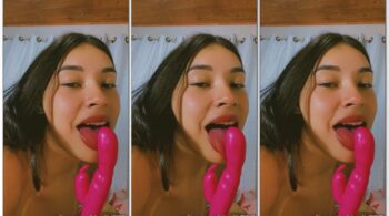 Laura Silva aparece na câmera sensualmente passando a língua no vibrador com uma expressão provocante