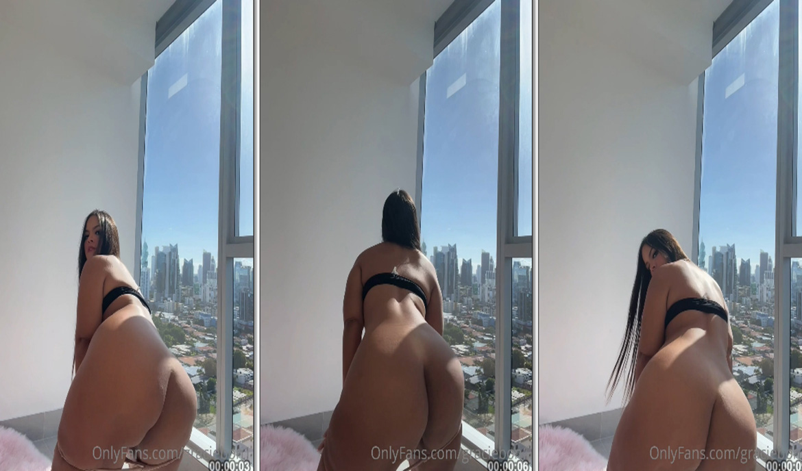 Gracie Bon, famosa do OnlyFans, dançando de forma ousada com a calcinha abaixada em frente à janela do apartamento