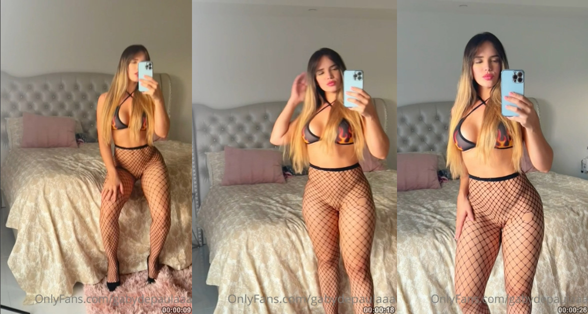 Gaby de Paula, conhecida do OnlyFans, posando de forma ousada no espelho sem calcinha, usando apenas meia calça