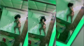 A modelo Amanda Luz, deitada na cama, se refletindo no espelho sem roupa